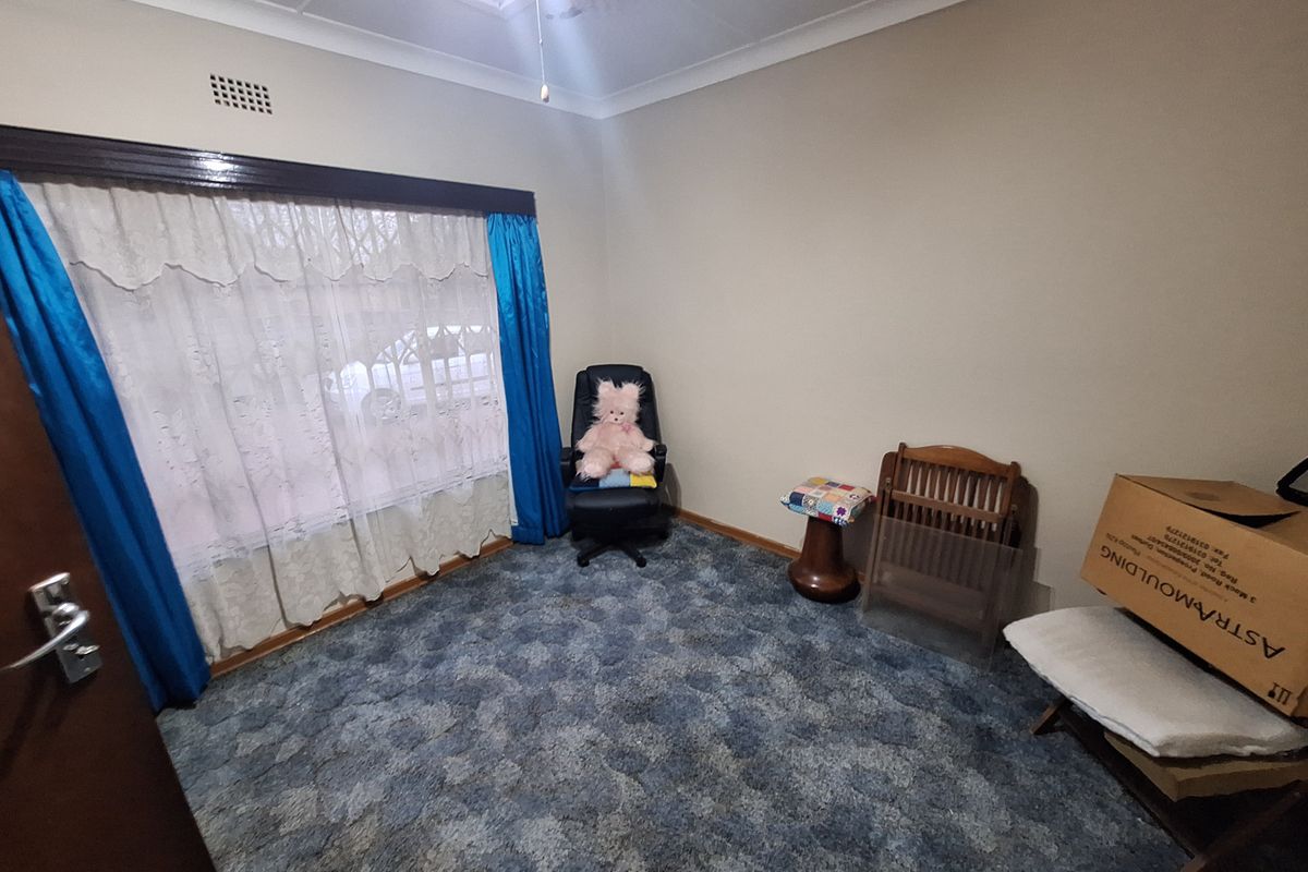 A bedroom featuring neutral wall tones, ceiling cornicing, and blue patterned carpet flooring, offering a blank canvas for potential interior updates.