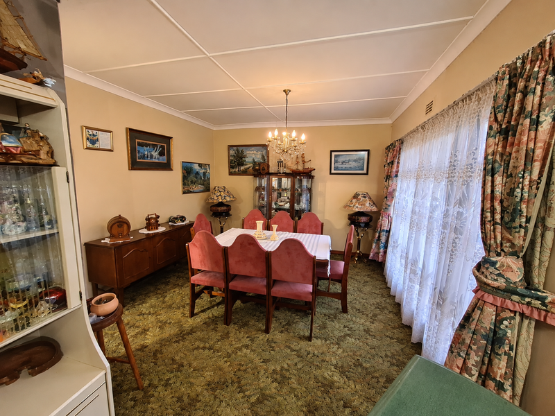 A traditional dining room featuring a tiled ceiling, coving, and large windows with curtains, offering a classic layout ready for modern updates.