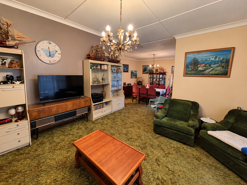 Spacious open-plan living and dining area featuring traditional chandeliers and coved ceilings, offering a versatile layout for family living.