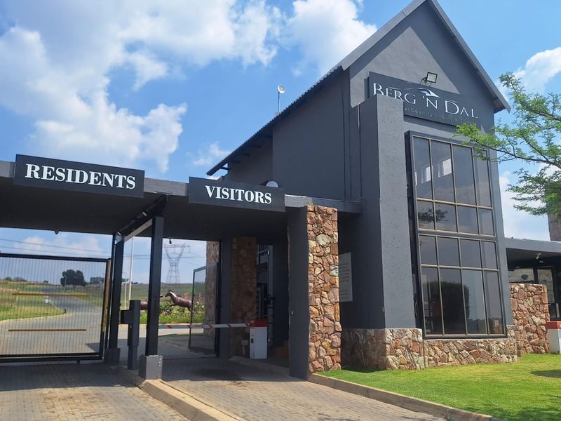The entrance gatehouse of Berg 'n Dal estate, featuring modern dark grey architecture, stone cladding, and dedicated access lanes for residents and visitors.