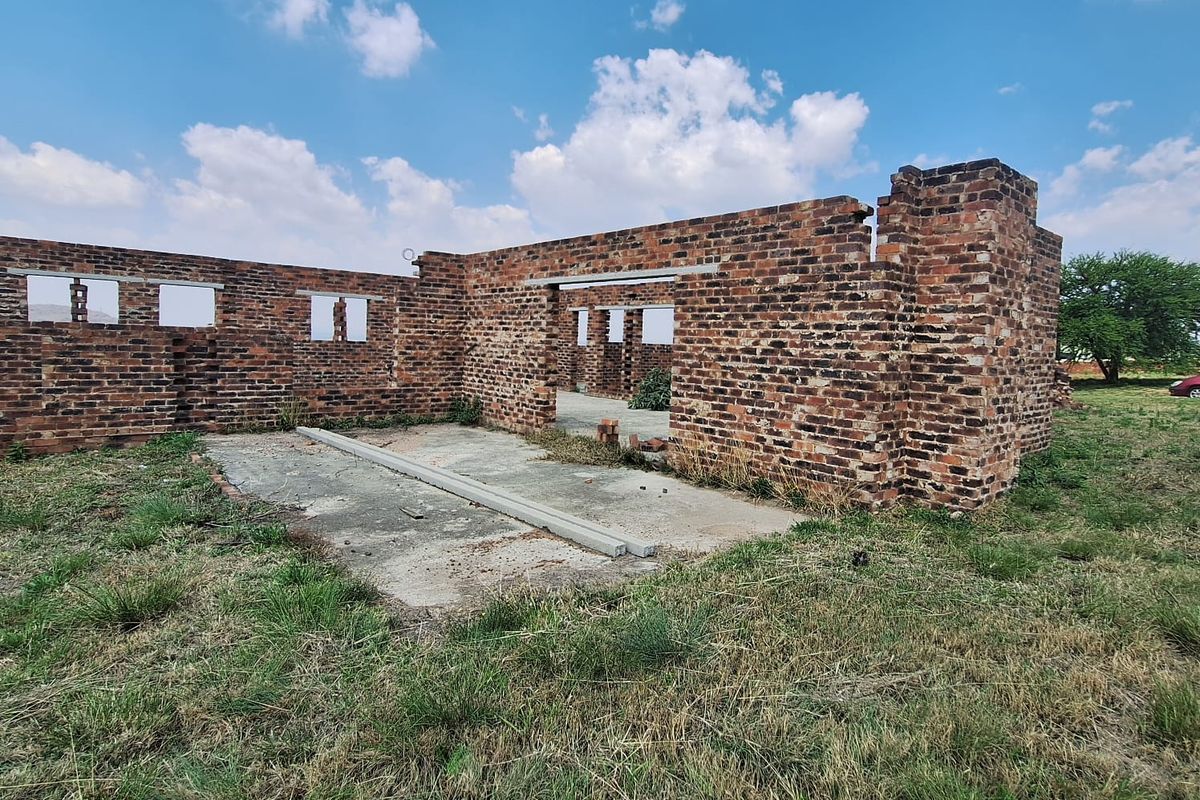 An incomplete brick structure showing the foundation and exterior walls, currently in a shell state requiring significant construction to complete.