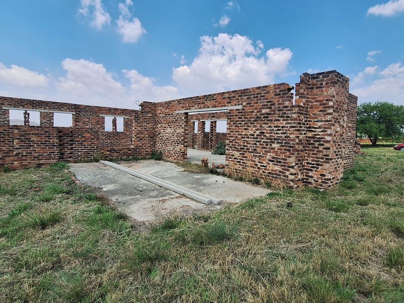 An incomplete brick structure showing the foundation and exterior walls, currently in a shell state requiring significant construction to complete.