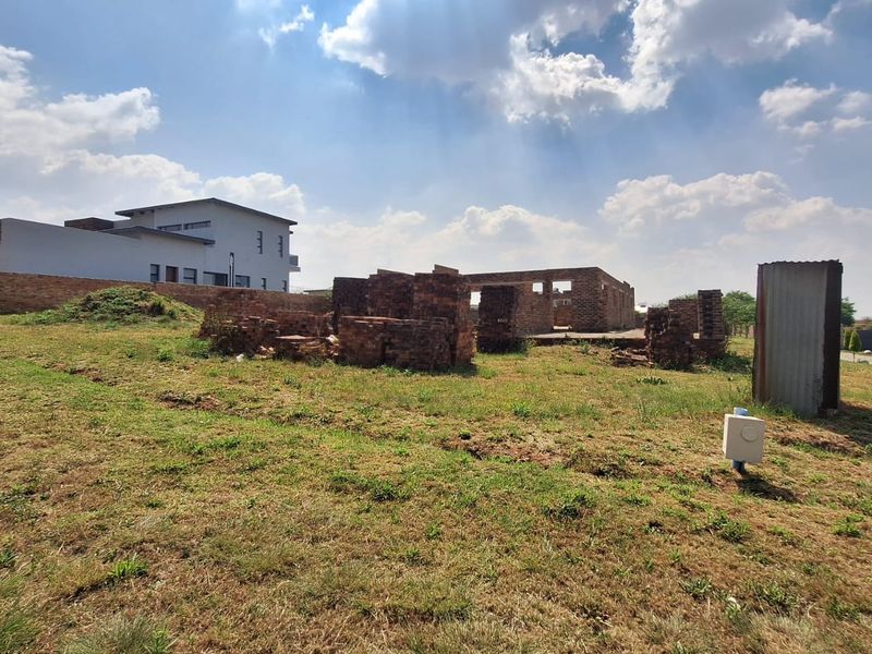 A vacant residential plot featuring incomplete brick construction and a boundary wall, offering a blank canvas for development.
