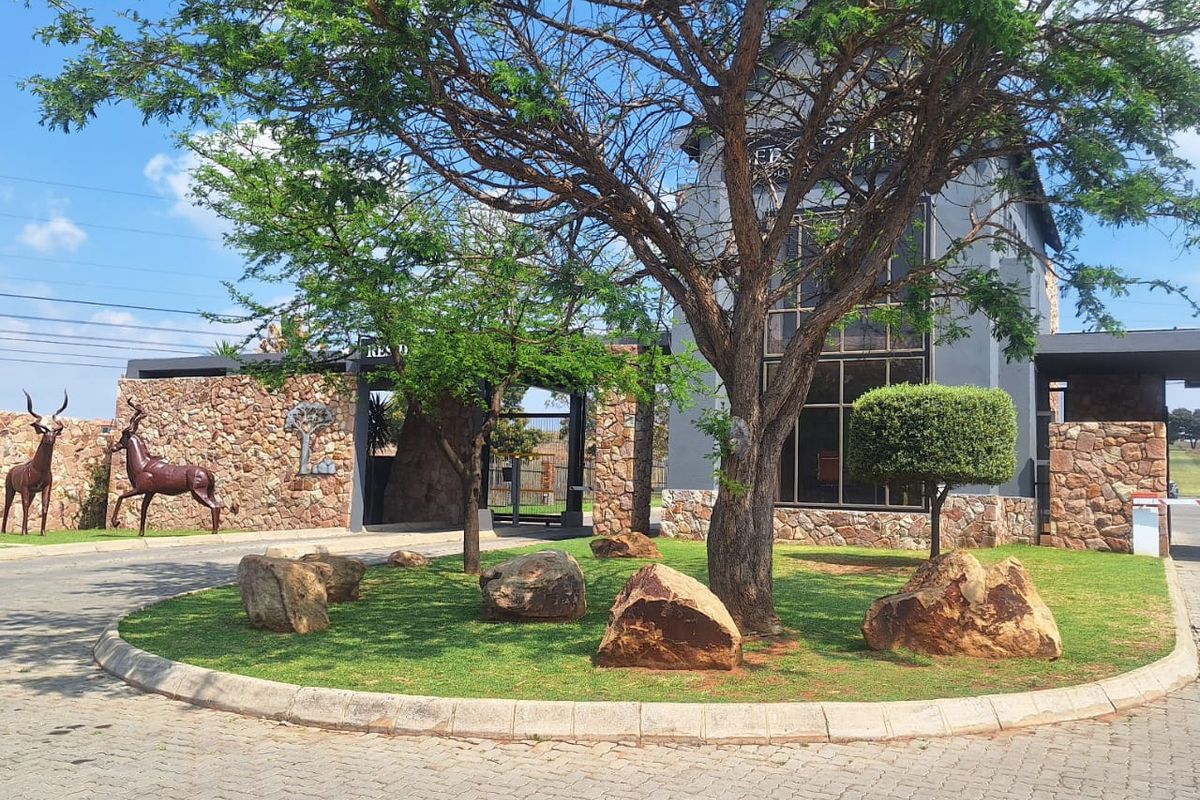 The front entrance of the property features stone cladding, a paved driveway, and a well-maintained landscaped garden with mature trees.