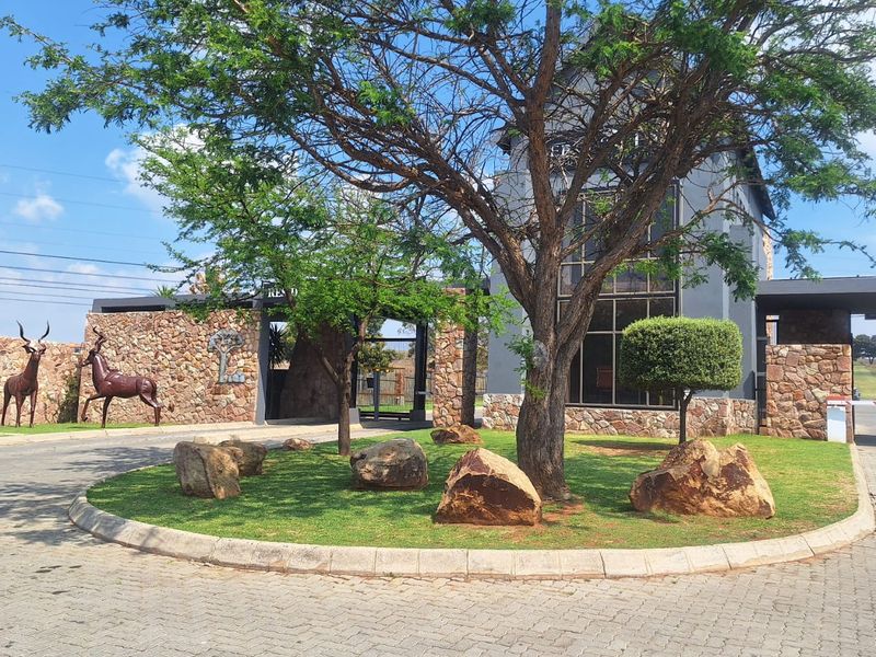 The front entrance of the property features stone cladding, a paved driveway, and a well-maintained landscaped garden with mature trees.