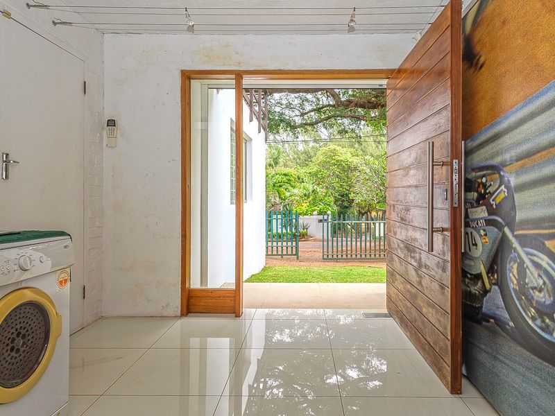 Entrance area featuring a large timber pivot door, tiled flooring, and track lighting, with direct access to the garden.