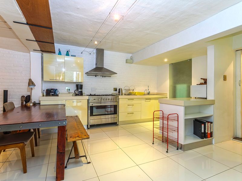 A modern kitchen featuring high-gloss cabinetry, stainless steel appliances, a gas hob, and tiled flooring, offering a functional and bright cooking space.