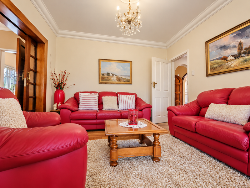 A well-maintained living room featuring classic crown molding, a crystal chandelier, and warm hardwood flooring, providing a comfortable and inviting atmosphere.