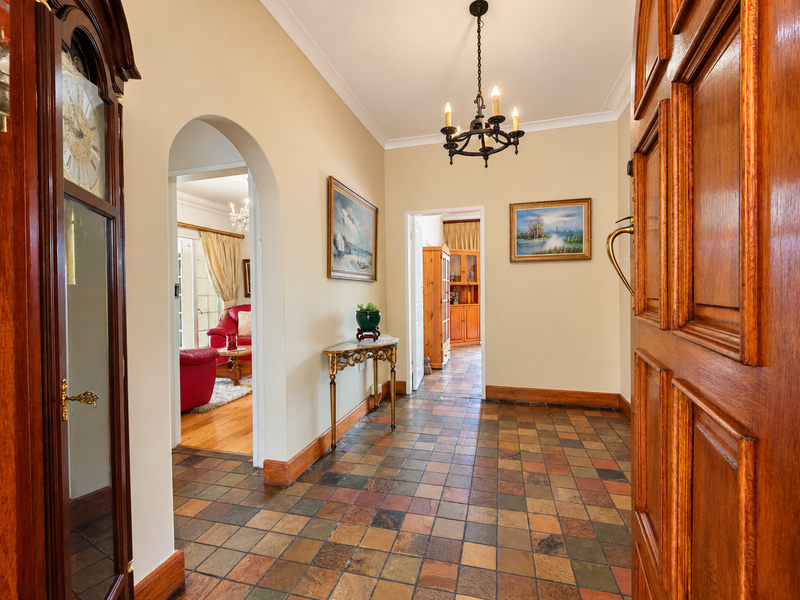 Welcoming entrance hall featuring classic tiled flooring, an elegant archway, and a traditional timber door, providing a warm transition into the home's living spaces.