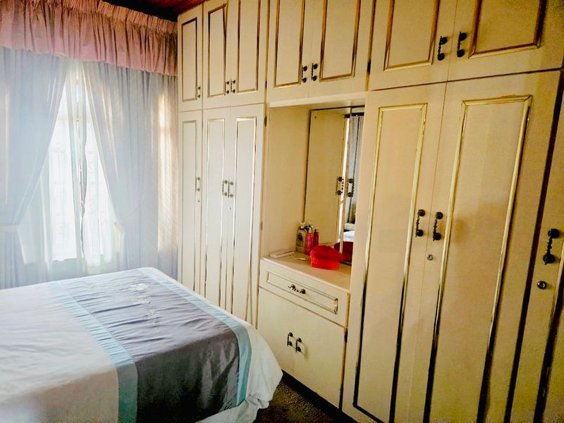 A bedroom featuring extensive floor-to-ceiling built-in cupboards with an integrated vanity and mirror, offering ample storage space.