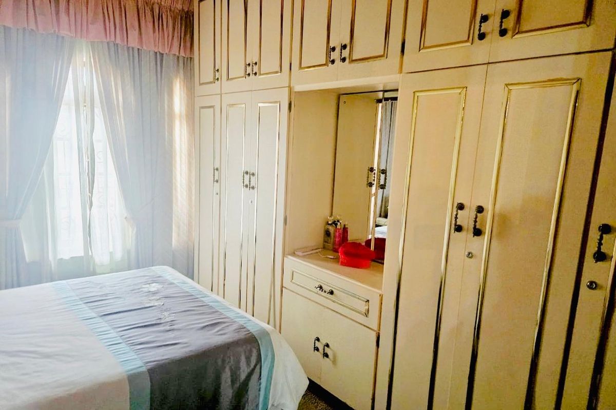A bedroom featuring extensive floor-to-ceiling built-in cupboards with an integrated vanity and mirror, offering ample storage space.