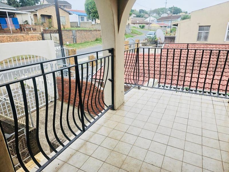 A covered balcony featuring tiled flooring and a decorative wrought iron balustrade, offering an elevated view of the surrounding residential neighborhood.
