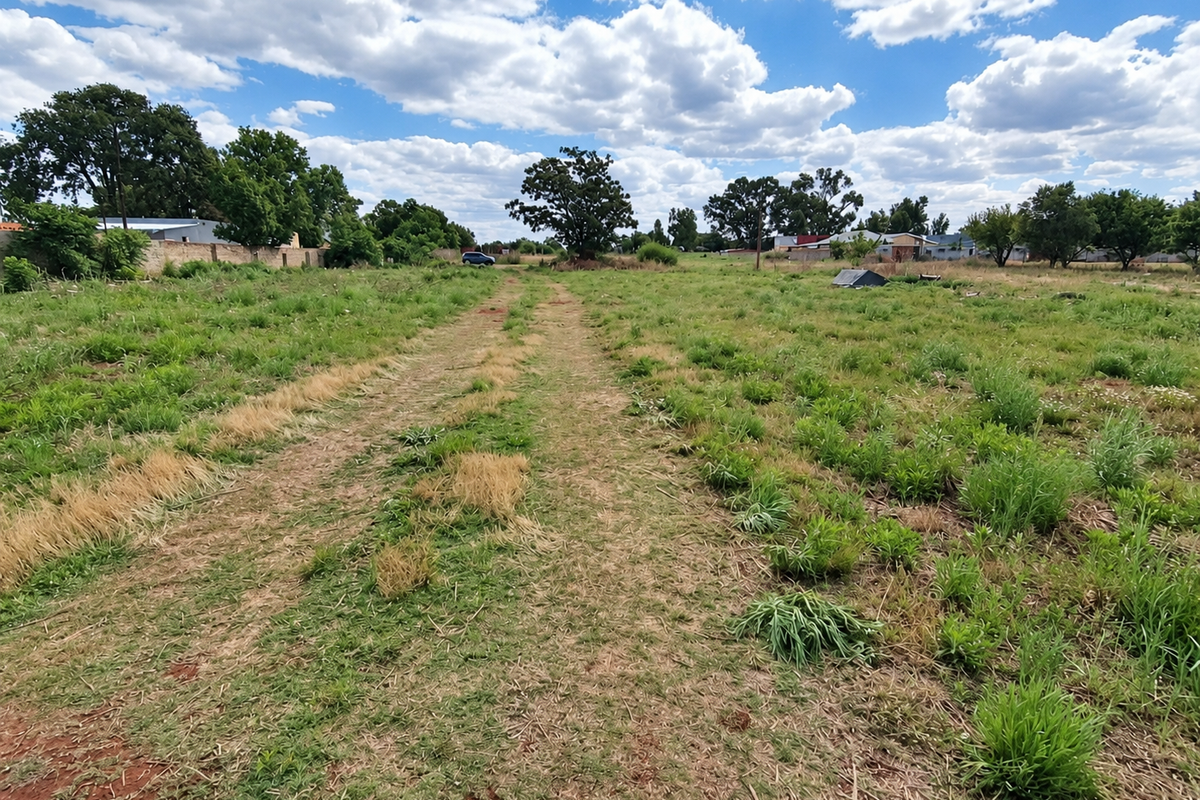 A spacious, level residential vacant land plot featuring established trees and perimeter walling, offering a blank canvas for future development.
