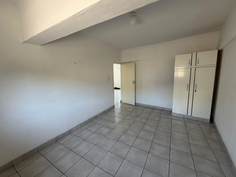 An empty bedroom featuring tiled flooring and a built-in wardrobe, offering a blank canvas for personalization.