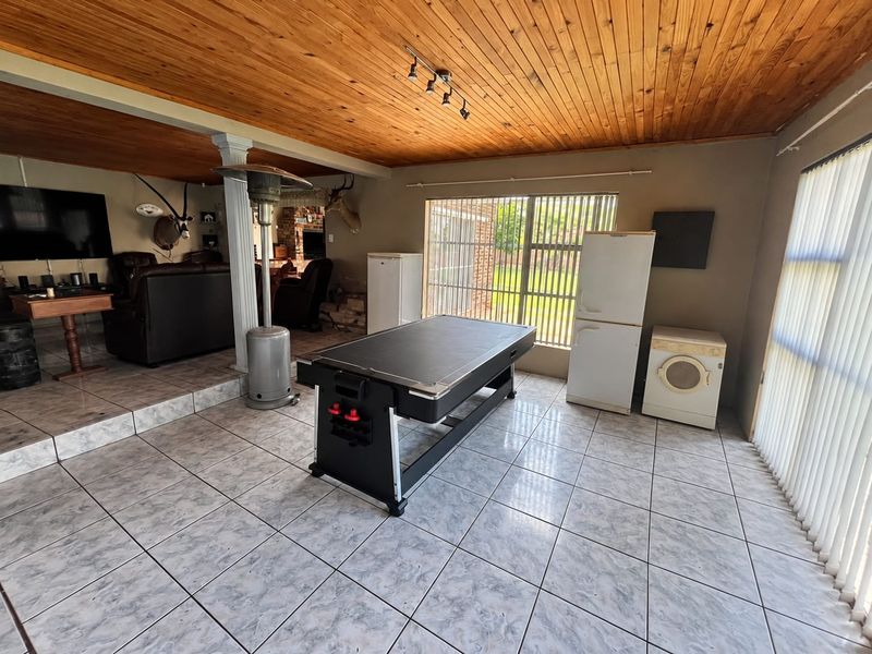 Spacious open-plan living area featuring a timber-clad ceiling, ceramic tiled flooring, and large sliding glass doors providing access to the exterior.