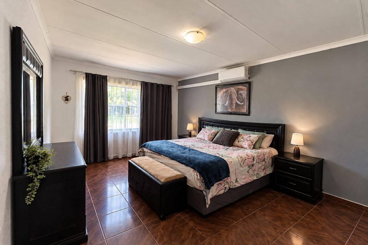 A well-maintained bedroom featuring tiled flooring, a split-system air conditioner, and neutral wall finishes.