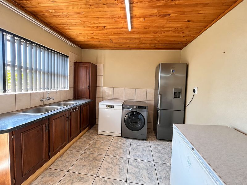 Functional laundry room featuring timber ceiling, tiled flooring, double basin sink, and built-in cabinetry with space for multiple appliances.