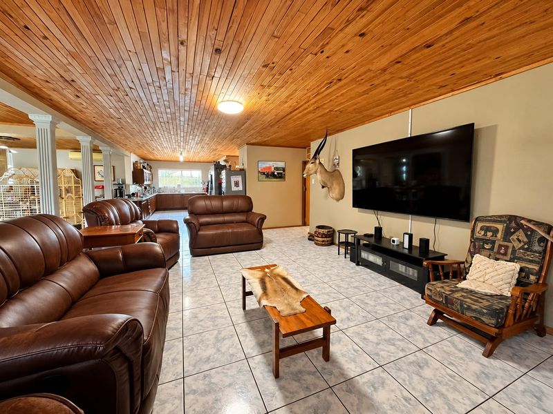 Spacious open-plan living area featuring a warm timber-clad ceiling, ceramic tiled flooring, and integrated kitchen space with classic cabinetry.
