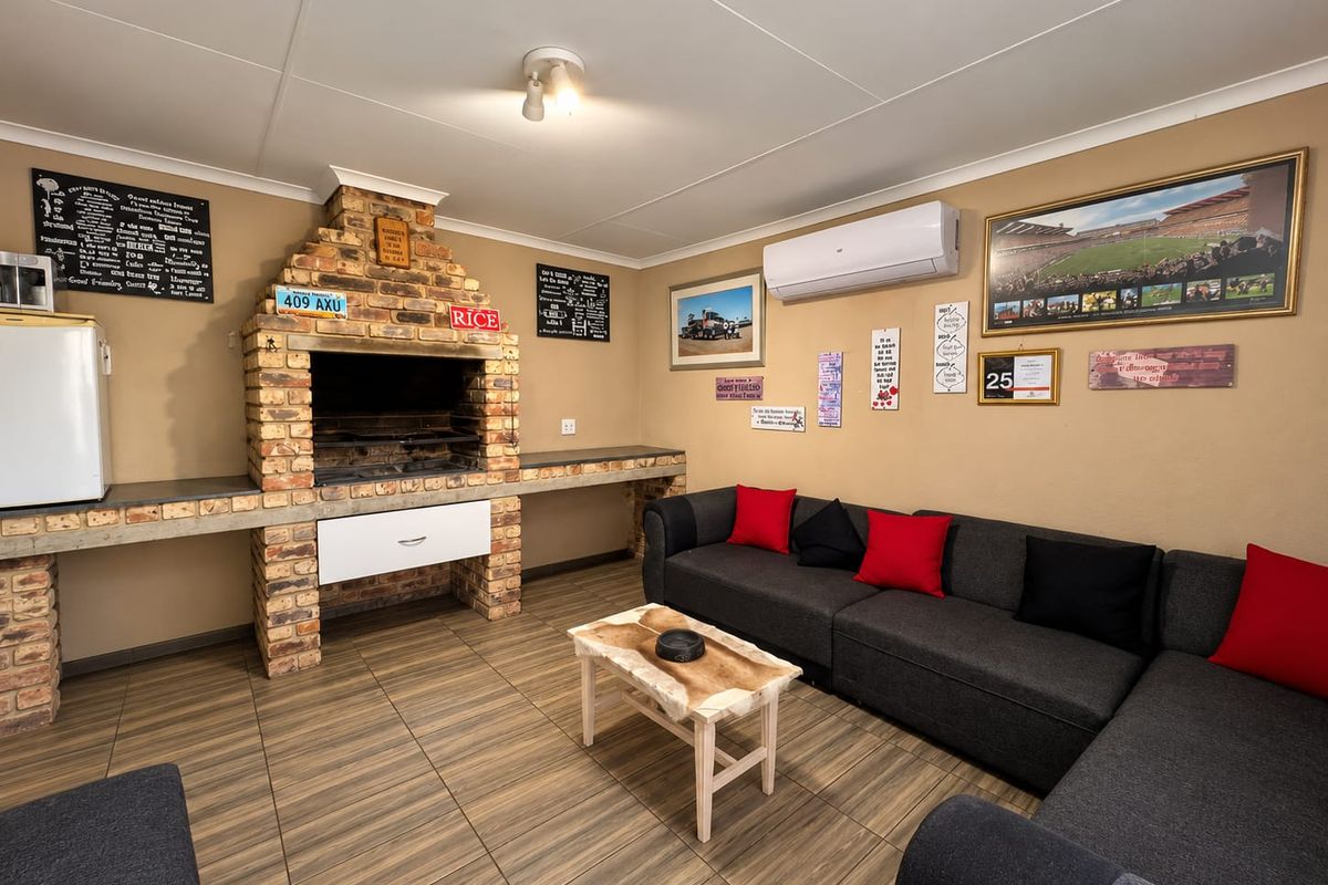 A comfortable living area featuring a prominent built-in brick fireplace with concrete counters and a wall-mounted air conditioning unit.