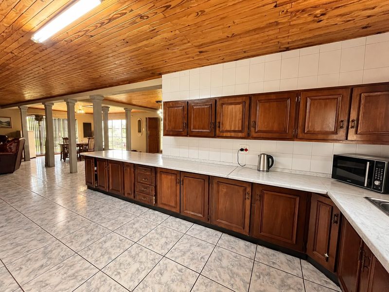 Spacious open-plan kitchen and living area featuring traditional wooden cabinetry, tiled flooring, and a distinctive wooden ceiling, offering a functional layout for family living.
