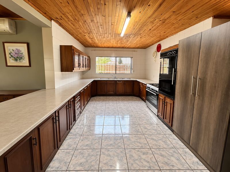 Spacious kitchen featuring extensive wooden cabinetry, laminate countertops, built-in oven, and a distinctive wooden tongue and groove ceiling with tiled flooring.