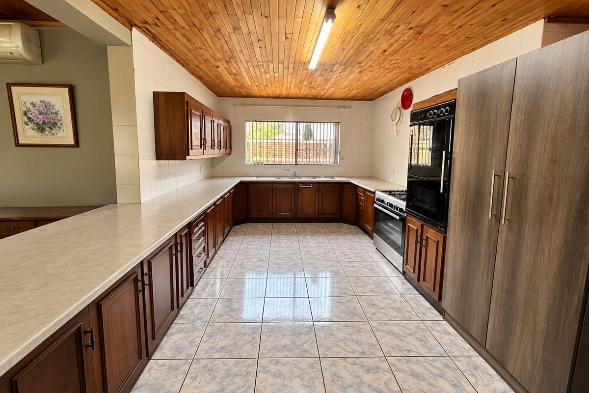 Spacious kitchen featuring extensive wooden cabinetry, laminate countertops, built-in oven, and a distinctive wooden tongue and groove ceiling with tiled flooring.