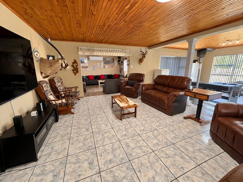 Spacious open-plan living area featuring a timber-clad ceiling, ceramic tiled flooring, and a split-system air conditioning unit.