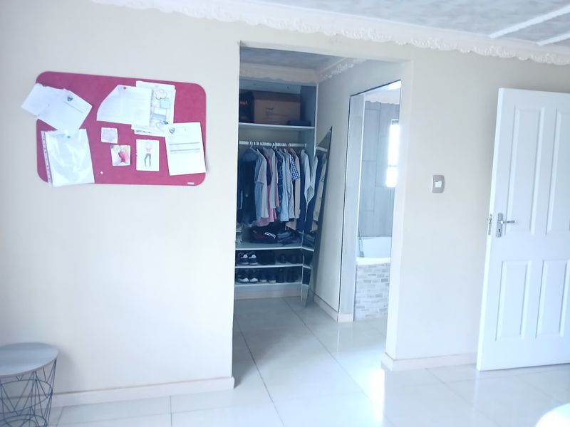 Bedroom featuring tiled flooring, decorative ceiling cornice, and a built-in wardrobe with direct access to an en-suite bathroom.