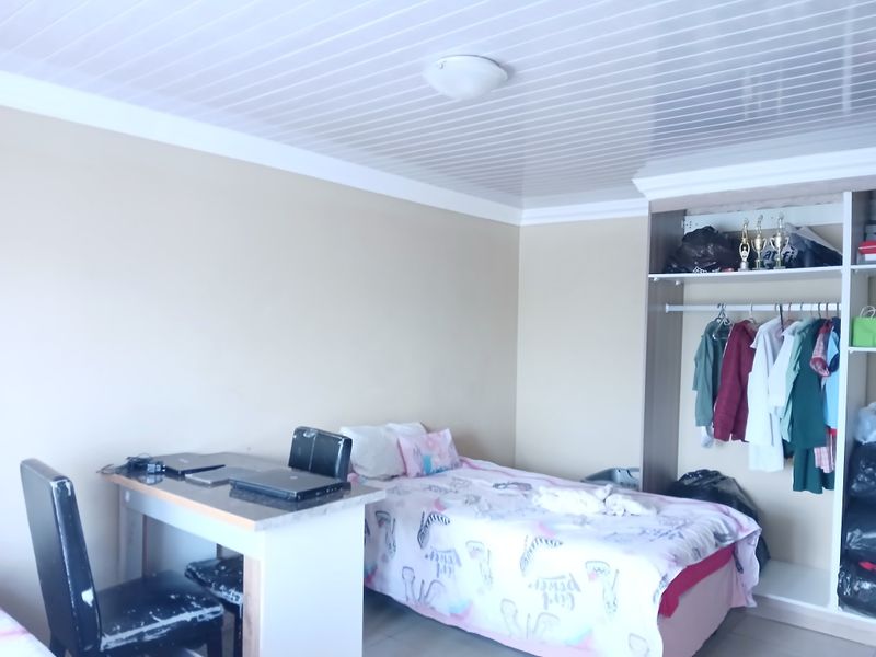 A functional bedroom featuring a built-in wardrobe and white panelled ceiling, offering a practical layout for comfortable living.