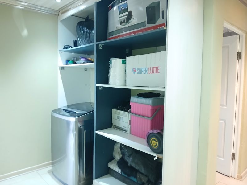 A functional laundry area featuring built-in storage shelving and tiled flooring, providing practical utility space within the home.