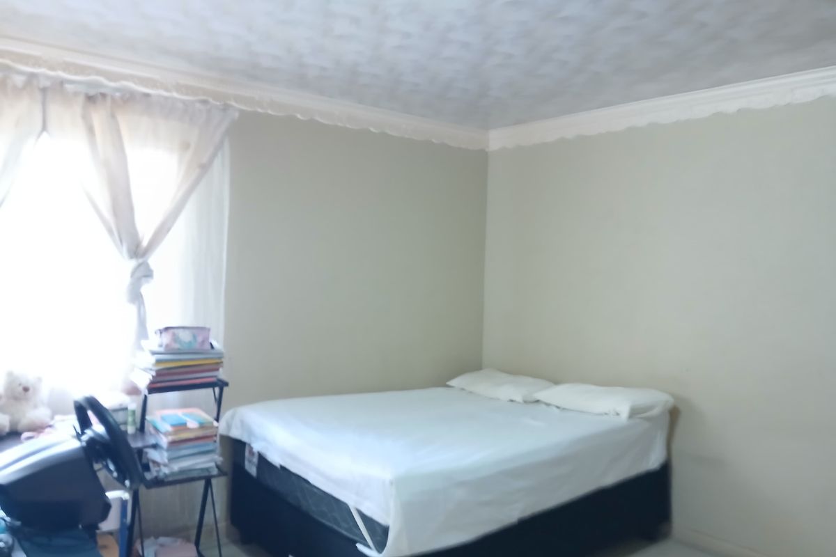 A simple bedroom featuring tiled flooring and decorative crown molding, providing a functional space with neutral wall tones.