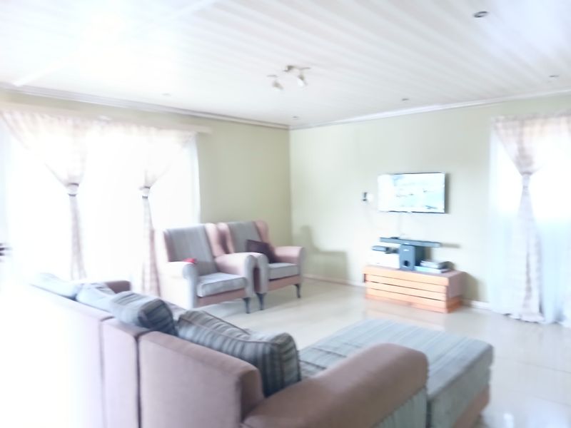A living room area featuring tiled flooring and recessed ceiling lighting, providing a functional space for relaxation.