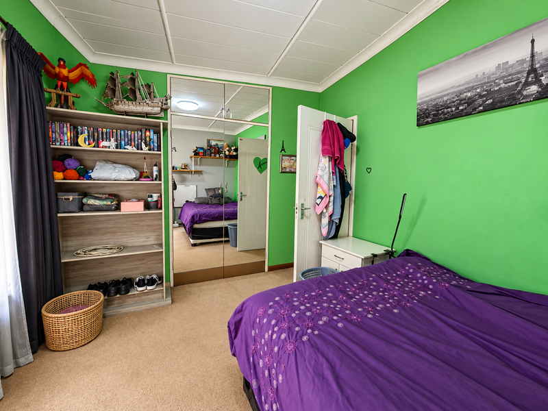 A bedroom featuring carpeted flooring, a built-in mirrored wardrobe, and a panelled ceiling, offering a functional space with potential for modernization.