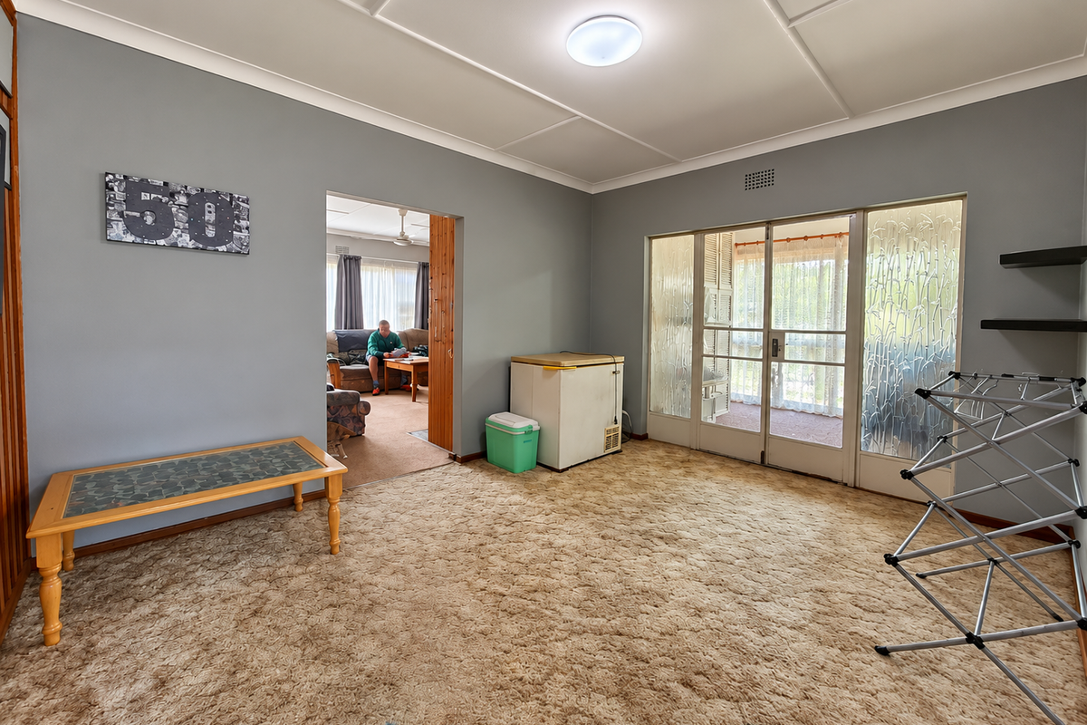 A spacious living area featuring carpet flooring, textured ceilings, and glass sliding doors providing access to an adjacent space.