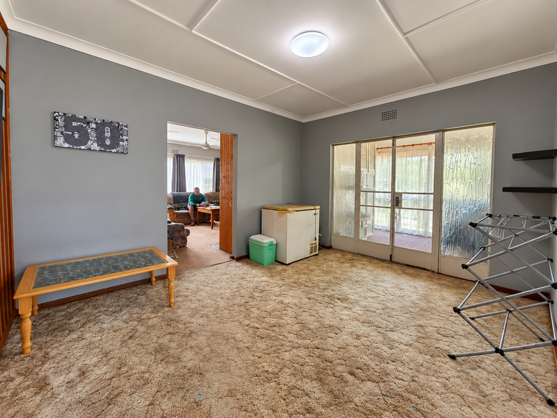 A spacious living area featuring carpet flooring, textured ceilings, and glass sliding doors providing access to an adjacent space.