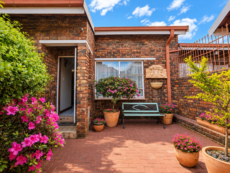 A well-maintained rear patio area featuring face brick walls, paved flooring, and established garden beds, providing a private outdoor space.