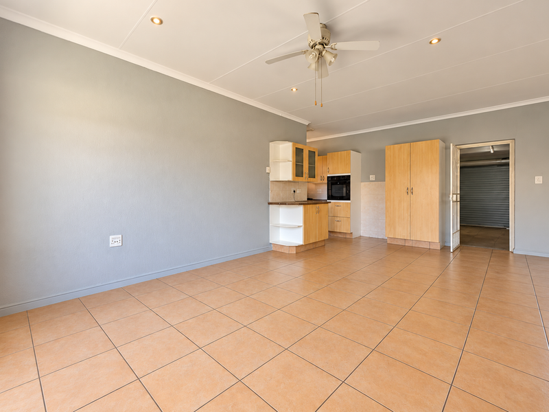 Spacious open-plan living area featuring tiled flooring, recessed lighting, a ceiling fan, and a compact built-in kitchen unit with an integrated oven.