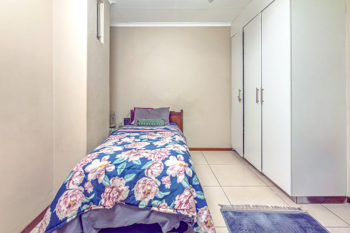 A functional bedroom featuring tiled flooring, a ceiling fan, and ample built-in cupboard storage space.