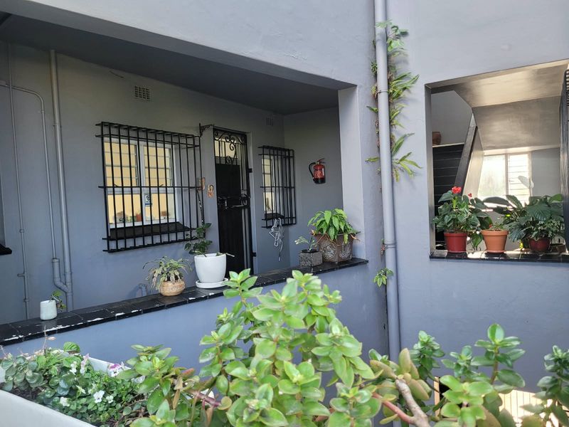 A view of the building exterior featuring security bars on windows, a security gate, and a fire extinguisher mounted on the wall.