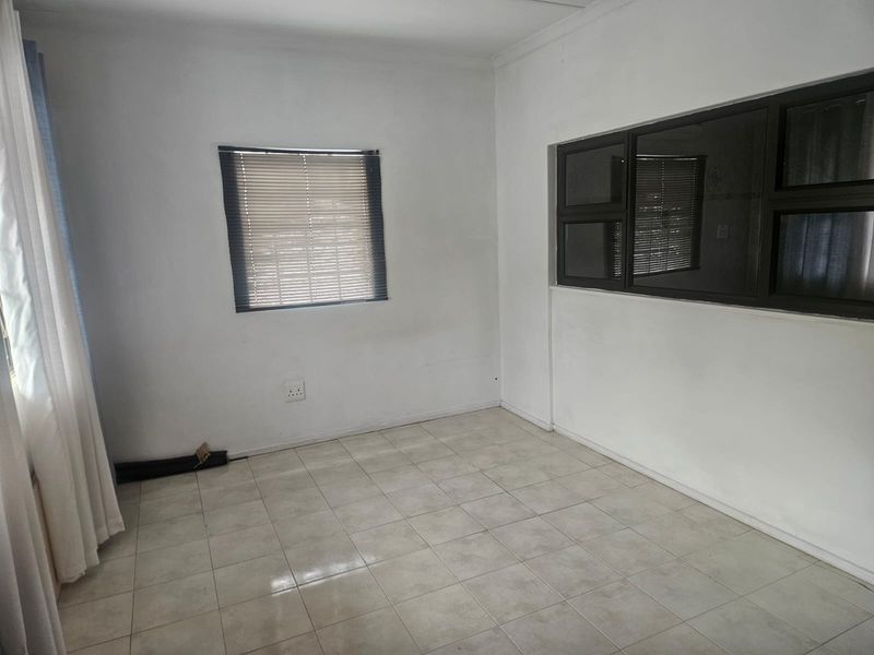 A vacant bedroom featuring neutral tiled flooring, aluminium window frames with fitted blinds, and clean white walls ready for personalization.