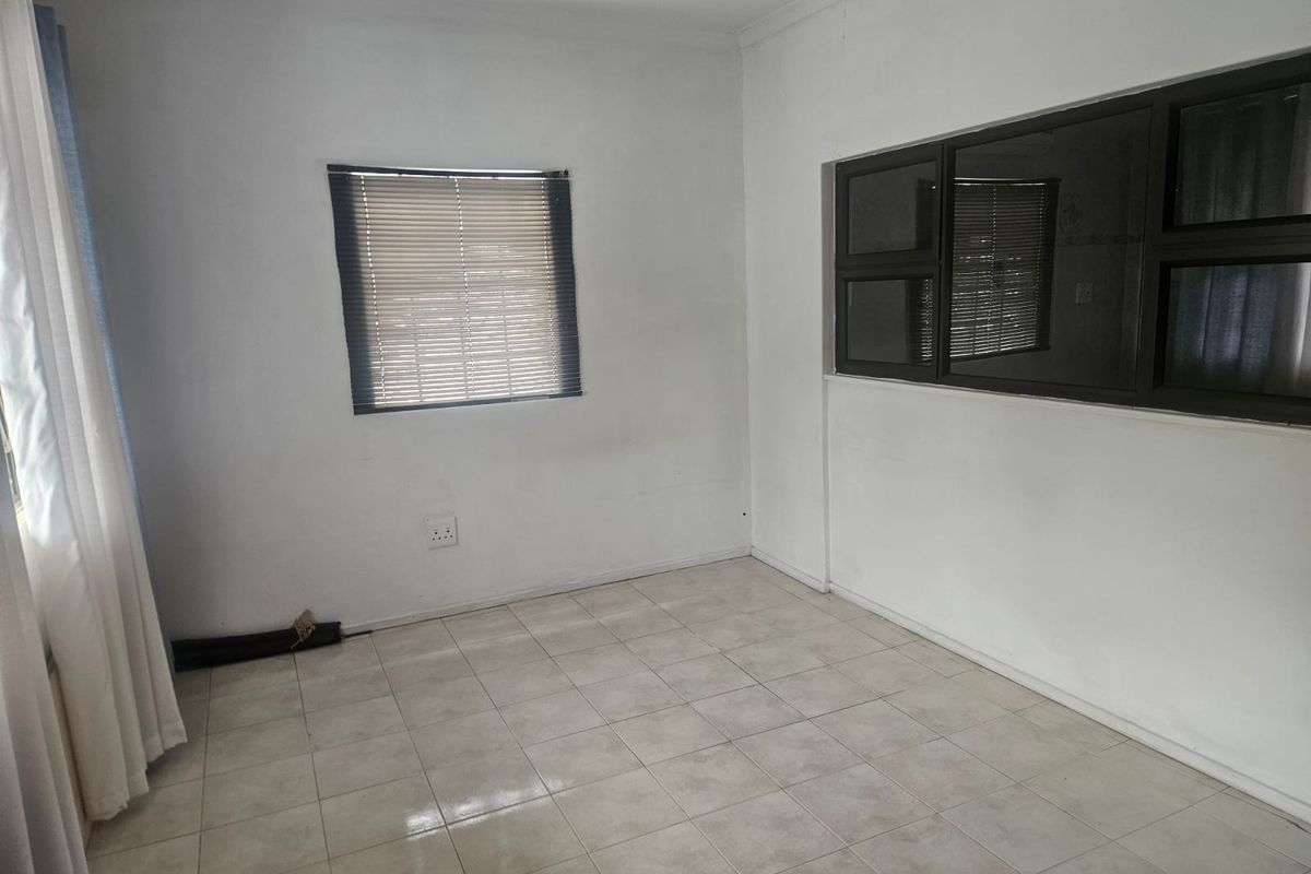 A vacant bedroom featuring neutral tiled flooring, aluminium window frames with fitted blinds, and clean white walls ready for personalization.