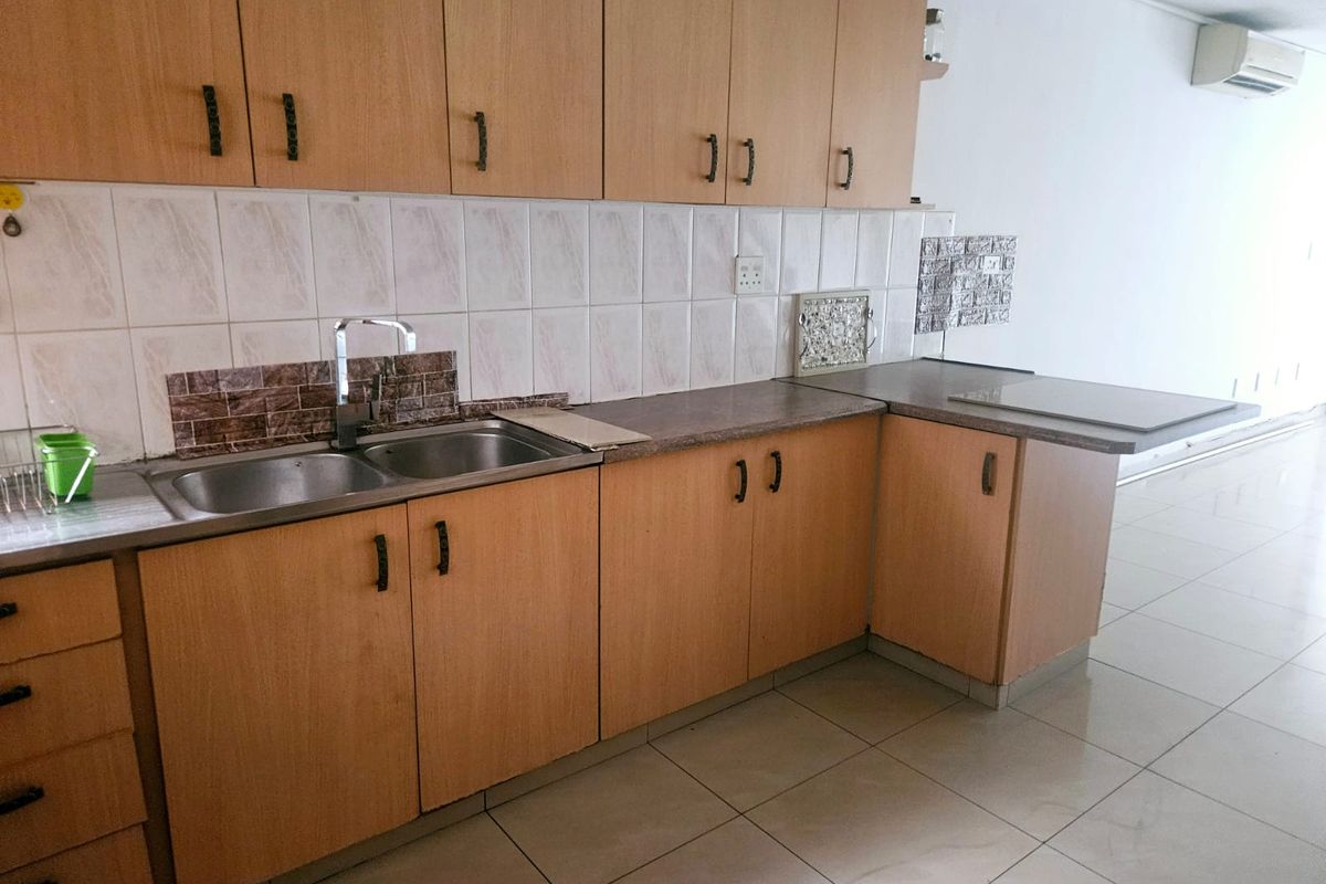 A functional kitchen featuring light wood-look laminate cabinetry, tiled backsplash, double stainless steel sink, and tiled flooring with an integrated air conditioning unit.
