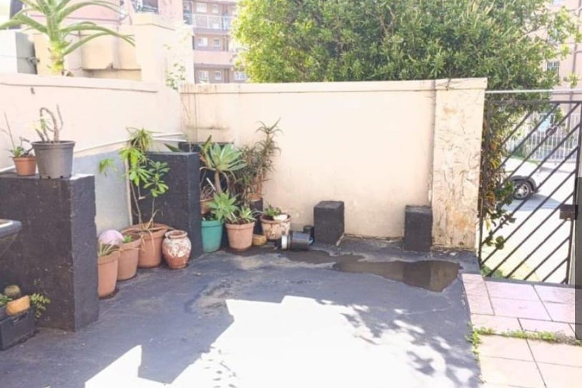A private rear courtyard area featuring boundary walls, a metal gate, and paved flooring, offering potential for outdoor landscaping and improvement.