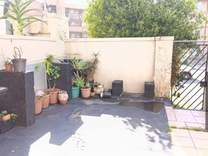 A private rear courtyard area featuring boundary walls, a metal gate, and paved flooring, offering potential for outdoor landscaping and improvement.