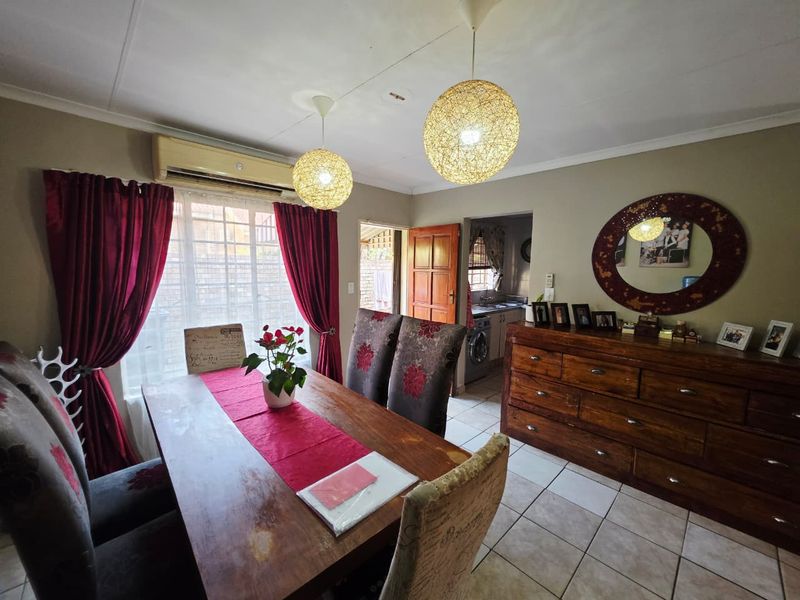 Dining room featuring tiled flooring, pendant lighting, and a wall-mounted air conditioning unit, with an adjacent view into the kitchen area.