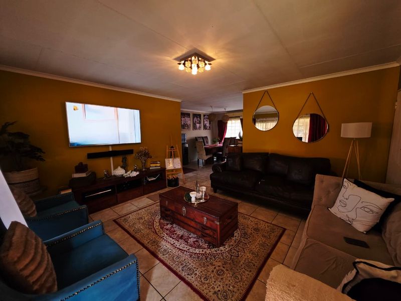 Spacious open-plan living and dining area featuring tiled flooring and warm wall tones, creating a comfortable and inviting atmosphere for family living.
