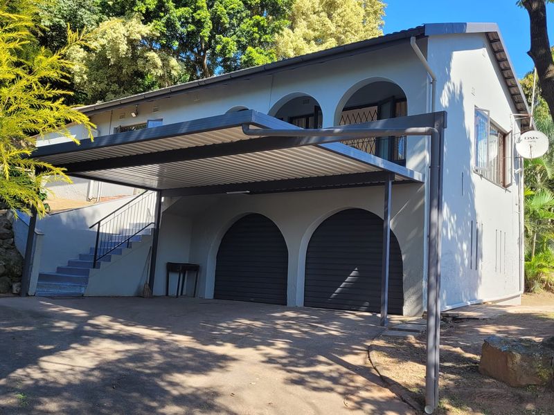 Front elevation of a multi-level house featuring a double garage, a modern carport, and an external staircase leading to the upper level.