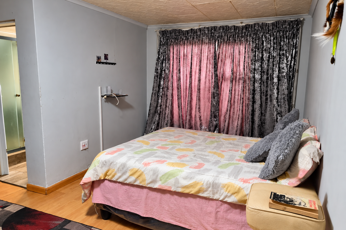 A bedroom featuring laminate flooring, textured ceiling tiles, and direct access to an en-suite bathroom.