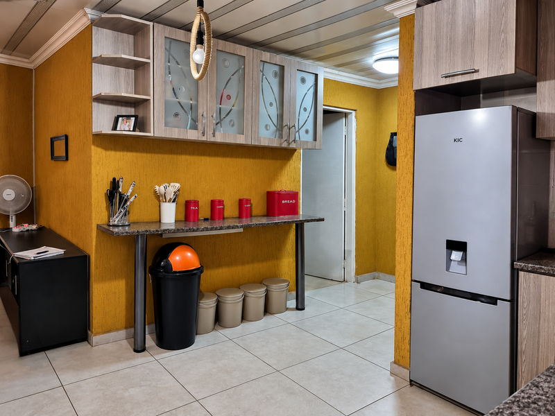 A functional kitchen area featuring built-in cabinetry, a laminate countertop, and tiled flooring, finished with vibrant yellow textured walls.
