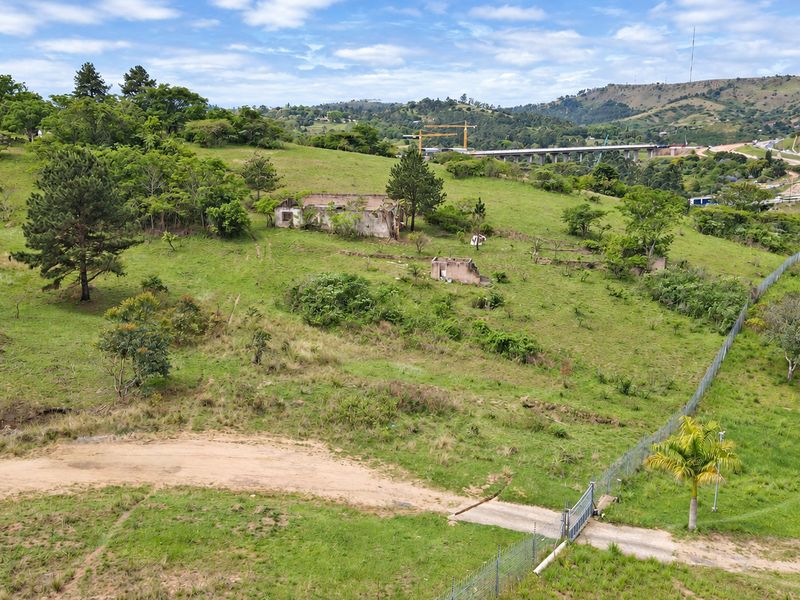 Aerial view of a large vacant residential plot featuring perimeter fencing, a gated entrance, and the remains of dilapidated structures on the property.